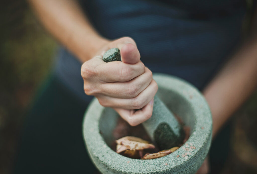 Person using pestle and mortar to grind food